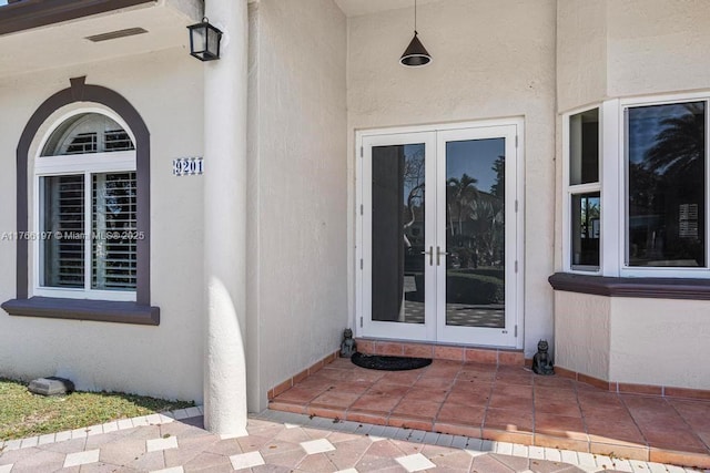 property entrance featuring stucco siding and french doors