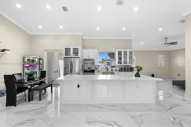 kitchen featuring a large island, a sink, backsplash, white cabinetry, and appliances with stainless steel finishes