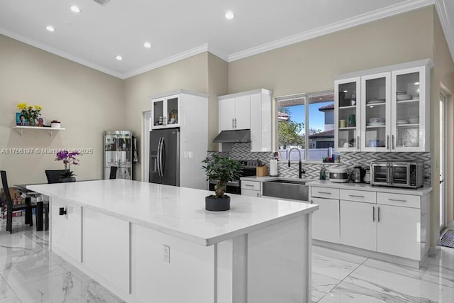kitchen with under cabinet range hood, refrigerator with ice dispenser, a sink, and marble finish floor