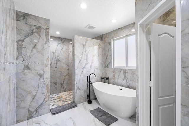 bathroom featuring a marble finish shower, a textured ceiling, a freestanding bath, tile walls, and marble finish floor
