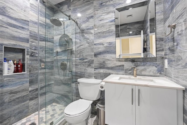 bathroom featuring a shower stall, vanity, tile walls, toilet, and visible vents