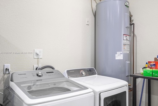 clothes washing area featuring water heater, a textured wall, laundry area, and independent washer and dryer