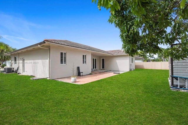 rear view of property featuring fence, a tiled roof, a yard, and stucco siding