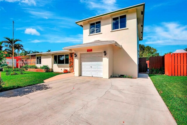 traditional-style home with fence, stucco siding, driveway, a front yard, and a garage
