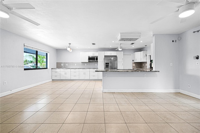 kitchen with a peninsula, a ceiling fan, stainless steel appliances, white cabinets, and tasteful backsplash