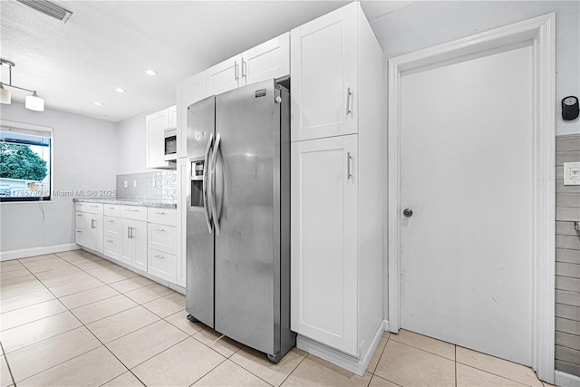 kitchen featuring light tile patterned floors, stainless steel fridge with ice dispenser, white cabinetry, and visible vents