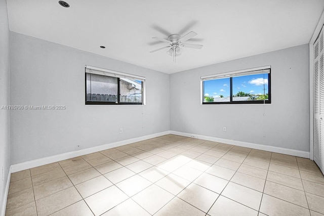 empty room featuring light tile patterned flooring, baseboards, and a ceiling fan