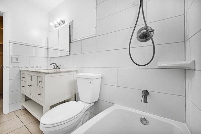 bathroom with tile walls, toilet, tile patterned floors, vanity, and a tub