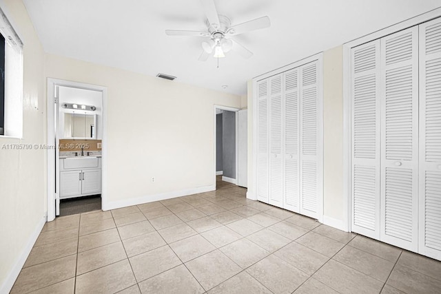 unfurnished bedroom with light tile patterned floors, baseboards, multiple closets, and visible vents
