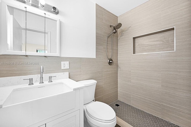 full bath featuring vanity, toilet, tile walls, and a tile shower