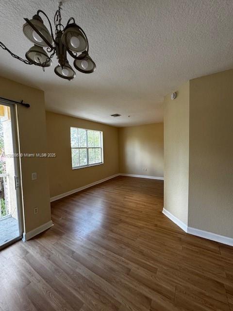 1017 Shoma Dr Unit 462, Royal Palm Beach, FL 33414 - empty room with baseboards, a notable chandelier, wood finished floors, and a textured ceiling