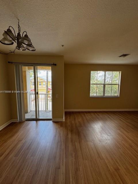 1017 Shoma Dr Unit 462, Royal Palm Beach, FL 33414 - empty room featuring wood finished floors, a textured ceiling, baseboards, a notable chandelier, and visible vents