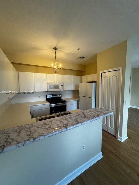 1017 Shoma Dr Unit 462, Royal Palm Beach, FL 33414 - kitchen featuring stainless steel range with electric cooktop, a peninsula, white microwave, baseboards, and freestanding refrigerator