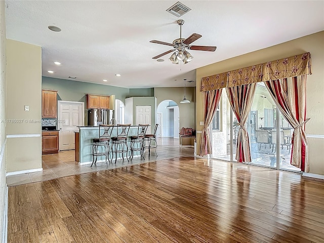 375 SW Dustin Ave, Port St Lucie, FL 34953 - unfurnished living room featuring light wood-style floors, arched walkways, a ceiling fan, baseboards, and visible vents