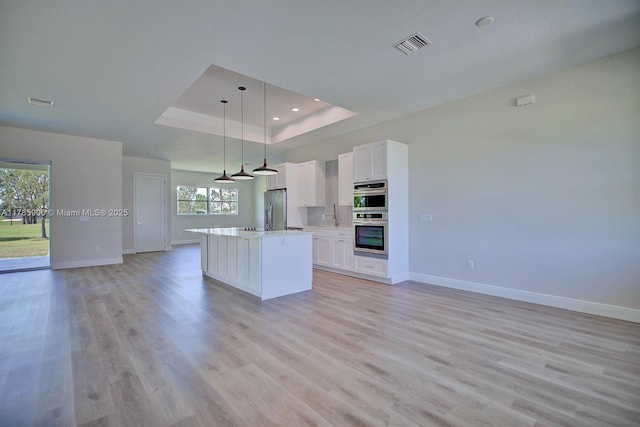 kitchen featuring stainless steel appliances, a center island, open floor plan, visible vents, and baseboards