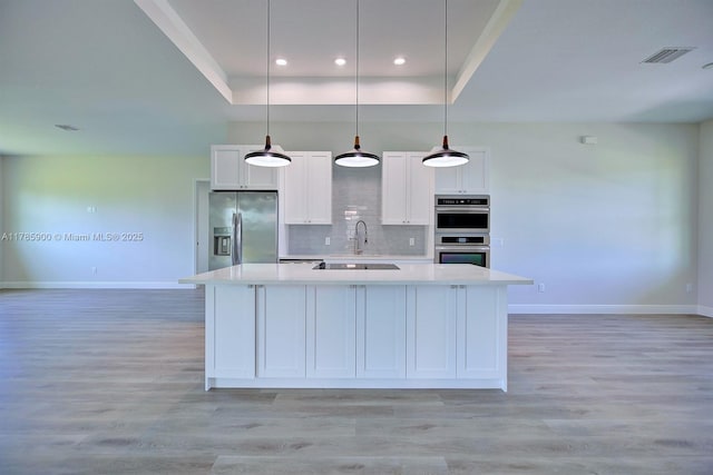 kitchen with stainless steel appliances, baseboards, visible vents, light countertops, and a raised ceiling