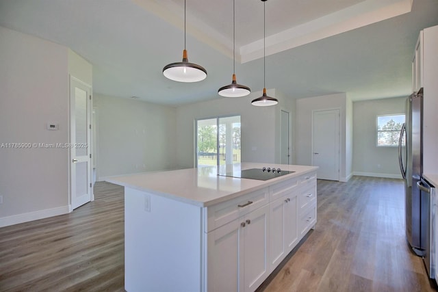 kitchen with wood finished floors, a healthy amount of sunlight, black electric cooktop, baseboards, and white cabinetry
