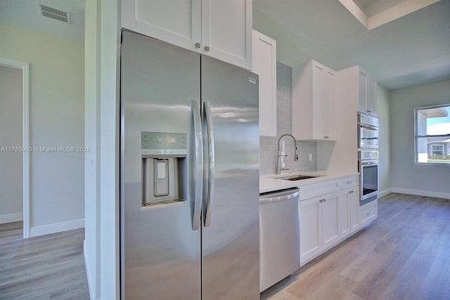 kitchen with light wood finished floors, visible vents, appliances with stainless steel finishes, and a sink