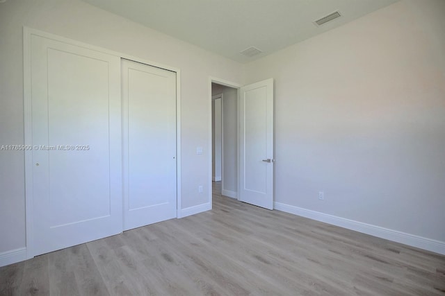 unfurnished bedroom with visible vents, baseboards, light wood-style floors, and a closet