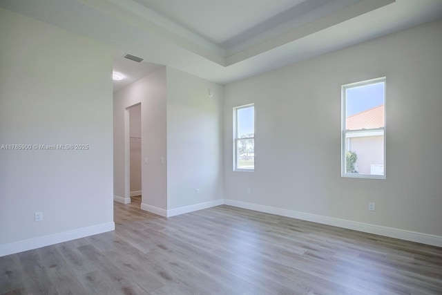 empty room with wood finished floors, visible vents, and baseboards