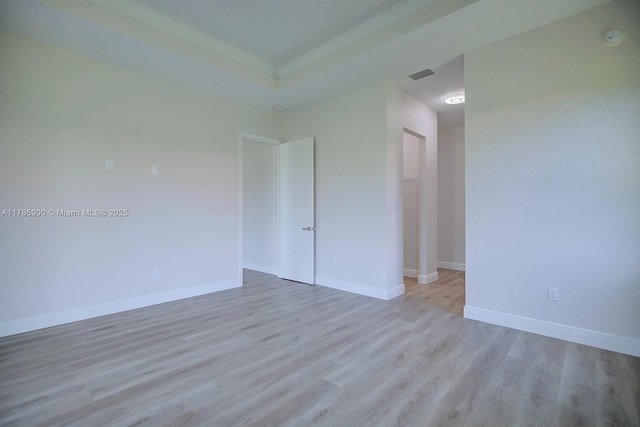 spare room featuring baseboards, wood finished floors, and visible vents
