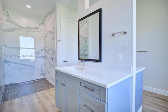 bathroom featuring vanity, wood finished floors, and a marble finish shower