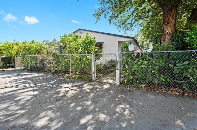 exterior space with a gate, fence, and stucco siding