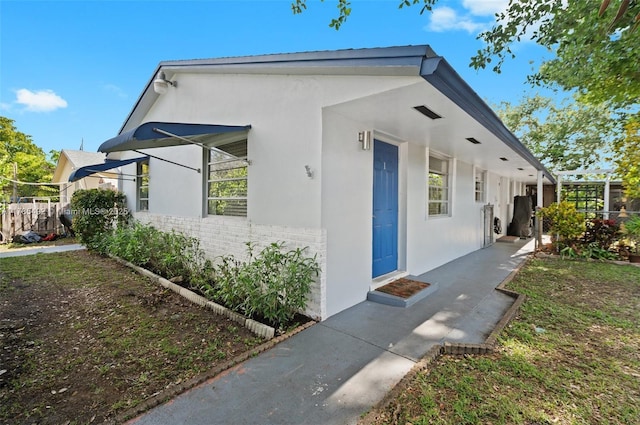 view of home's exterior featuring fence, brick siding, and stucco siding