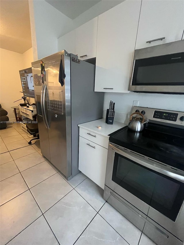 kitchen featuring light tile patterned floors, light countertops, white cabinetry, and appliances with stainless steel finishes