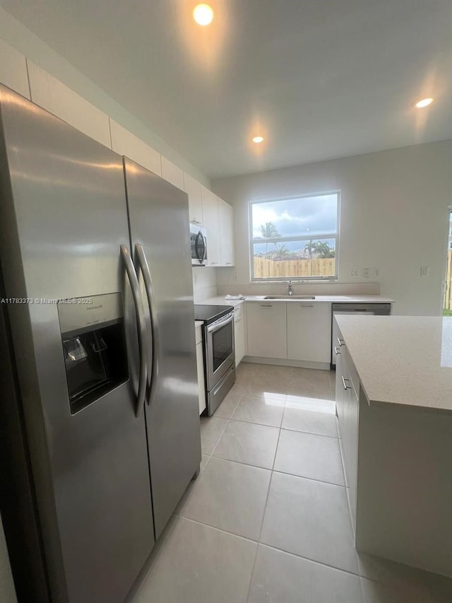 kitchen with a sink, recessed lighting, white cabinetry, appliances with stainless steel finishes, and light tile patterned floors