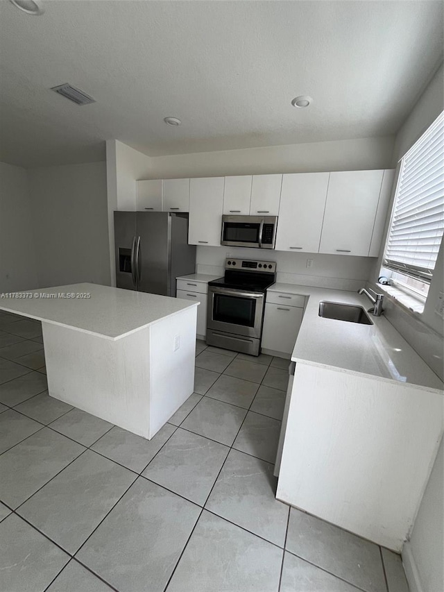 12121 NW 23rd Ct Unit 12121, Miami, FL 33167 - kitchen featuring appliances with stainless steel finishes, white cabinetry, light countertops, light tile patterned floors, and a center island