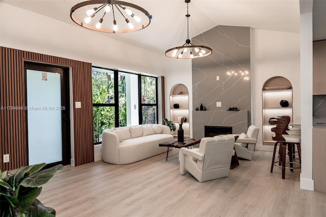 751 NE 80th St, Miami, FL 33138 - living room with light wood-type flooring, a chandelier, built in shelves, high vaulted ceiling, and a high end fireplace
