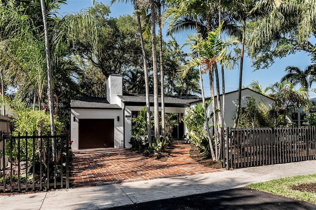 751 NE 80th St, Miami, FL 33138 - view of front facade featuring a fenced front yard, a chimney, an attached garage, stucco siding, and roof with shingles