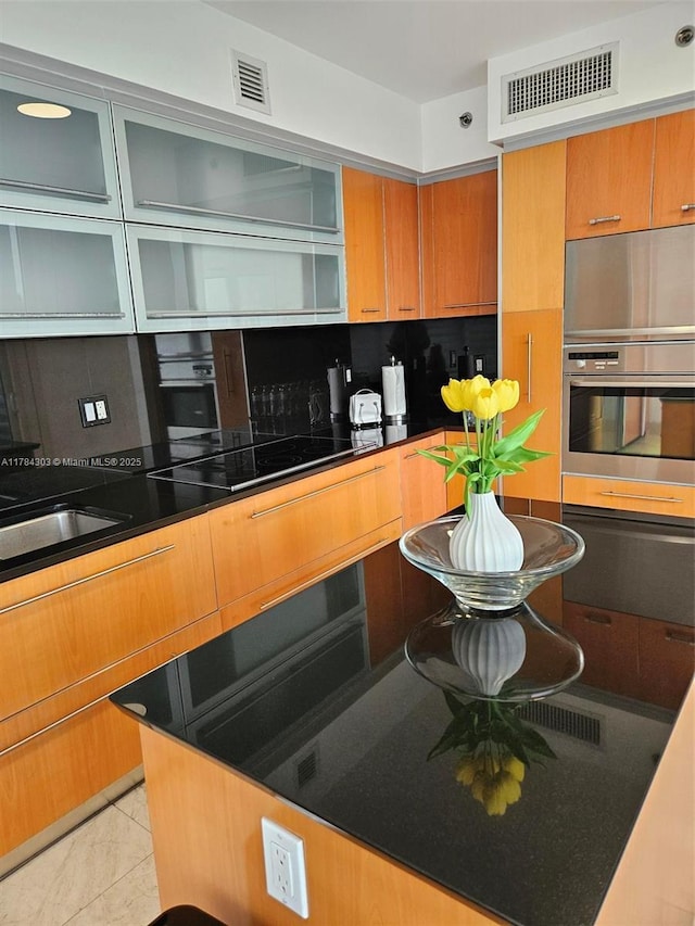 kitchen featuring stainless steel oven, decorative backsplash, visible vents, and brown cabinets