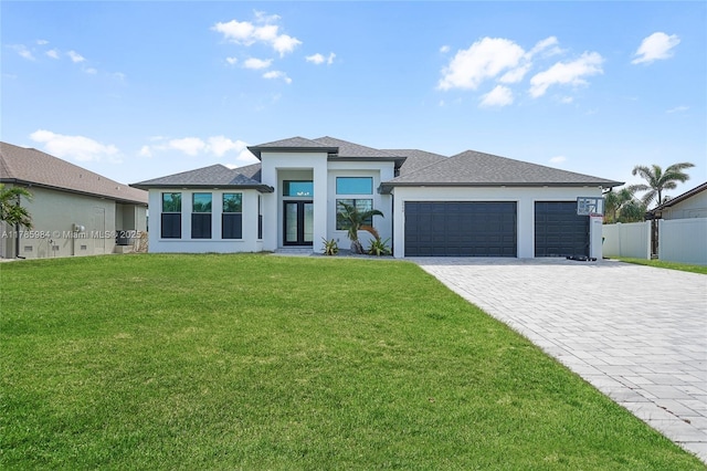 prairie-style home featuring a front lawn, fence, an attached garage, stucco siding, and decorative driveway