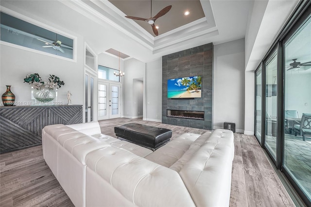 living room with a tray ceiling, wood finished floors, and ceiling fan with notable chandelier