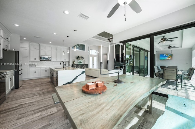 dining area featuring light wood finished floors, a ceiling fan, and visible vents