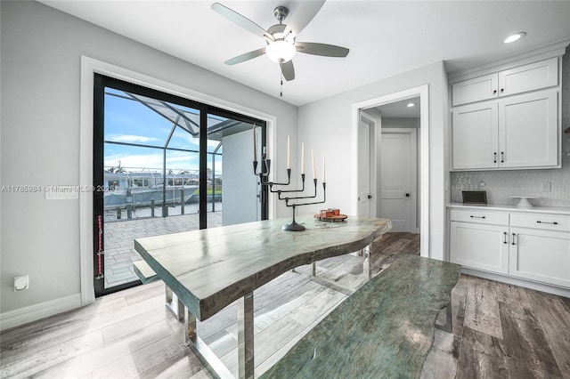 dining room featuring recessed lighting, a water view, a ceiling fan, light wood-type flooring, and baseboards