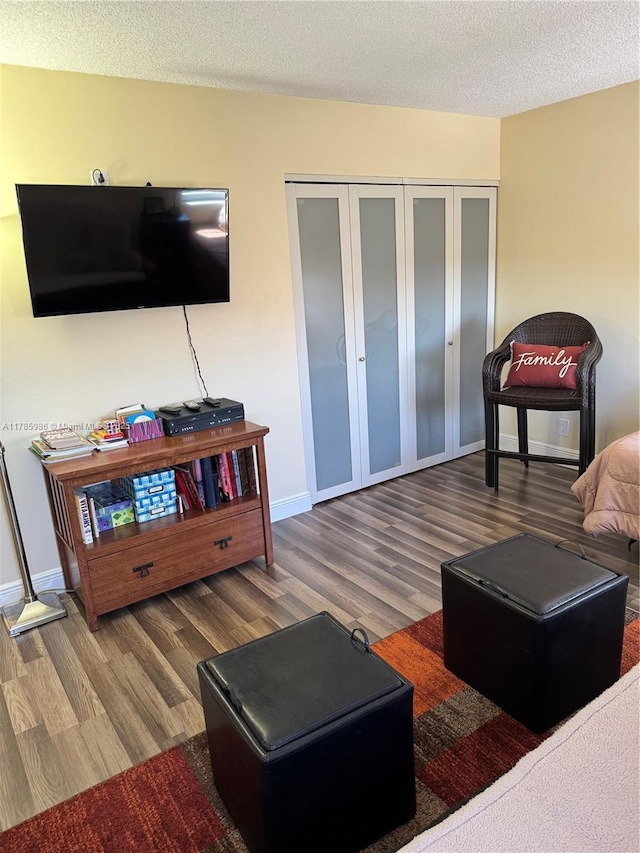 living room featuring wood finished floors, a textured ceiling, and baseboards