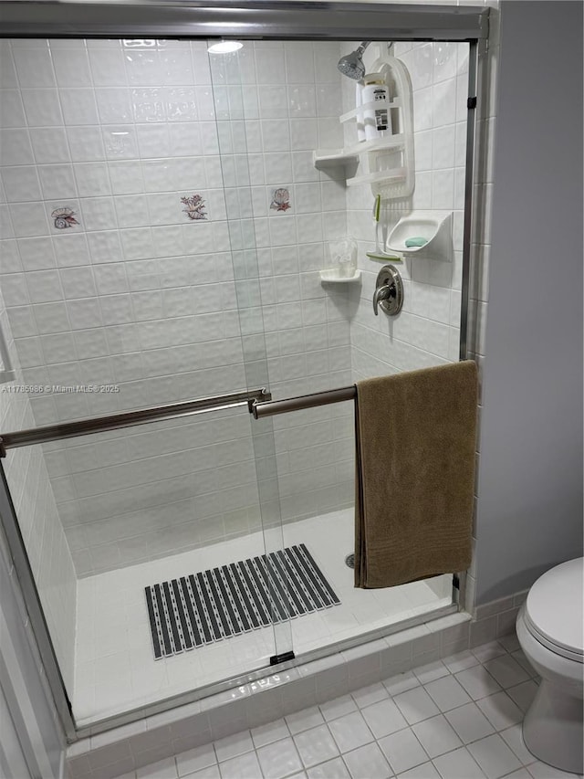 bathroom featuring tile patterned flooring, a stall shower, and toilet