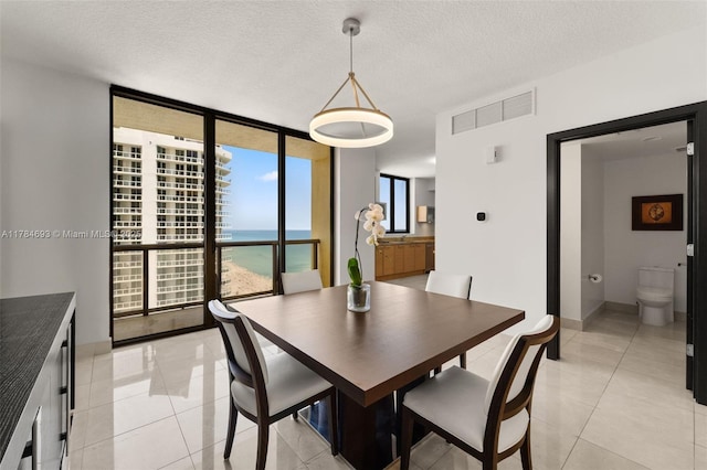 16275 Collins Ave Unit 2202, Sunny Isles Beach, FL 33160 - dining room featuring a wall of windows, light tile patterned flooring, a water view, a textured ceiling, and baseboards