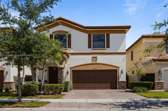 10075 NW 86th Ter, Doral, FL 33178 - mediterranean / spanish house with a tile roof, decorative driveway, stone siding, an attached garage, and stucco siding