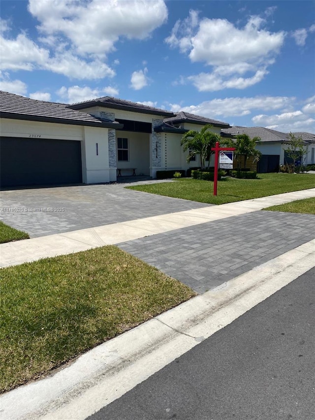 29074 SW 168th Ct, Homestead, FL 33030 - view of front of home featuring a front lawn, stucco siding, a tile roof, decorative driveway, and a garage