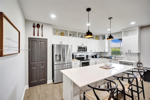 29074 SW 168th Ct, Homestead, FL 33030 - kitchen with stainless steel appliances, a breakfast bar, backsplash, light countertops, and light wood-style floors