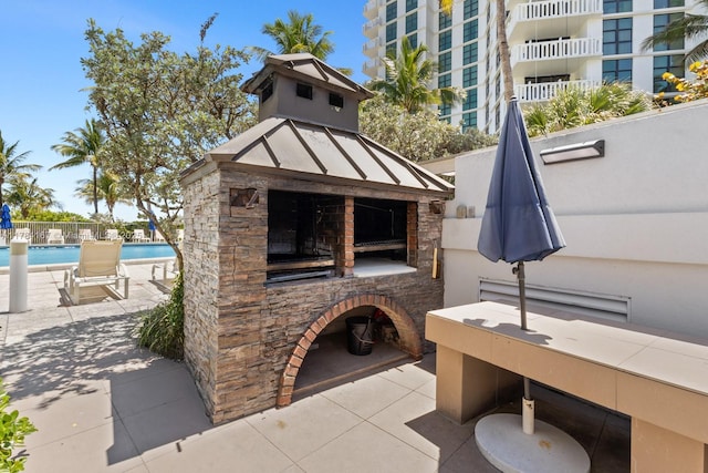 view of patio with a community pool, fence, and a fireplace