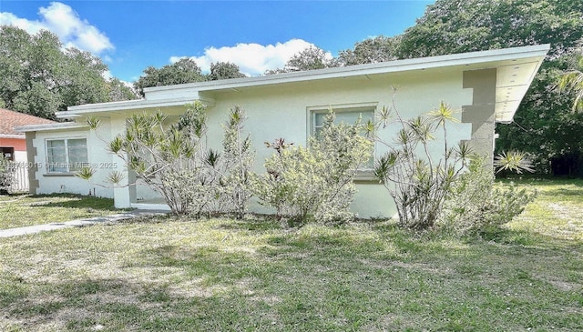 view of side of property with stucco siding and a lawn