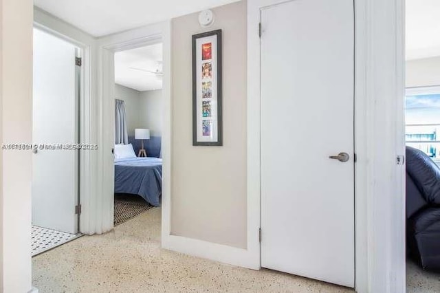 corridor featuring dark speckled floor and baseboards