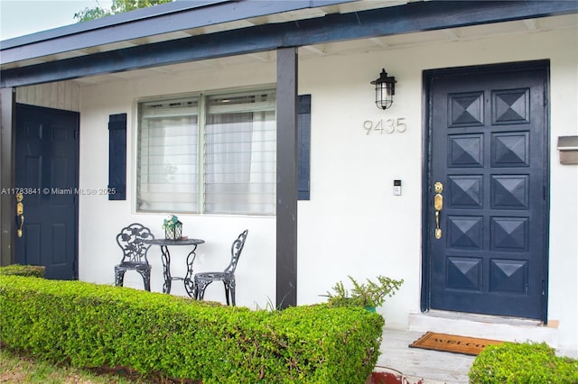 entrance to property featuring a porch and stucco siding