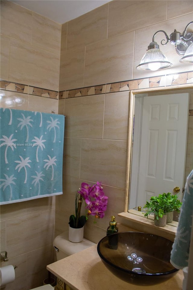half bath with tile walls, toilet, and vanity