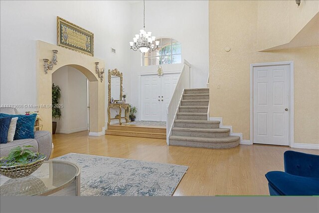 13063 NW 11th Ct, Sunrise, FL 33323 - foyer featuring a high ceiling, wood finished floors, a chandelier, arched walkways, and baseboards